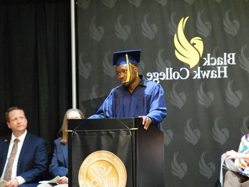 GED毕业生戴帽 & gown and speaking at podium on stage