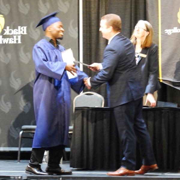 BHC总裁博士. Jeremy Thomas handing certificate to GED grad Tony Johnson on stage